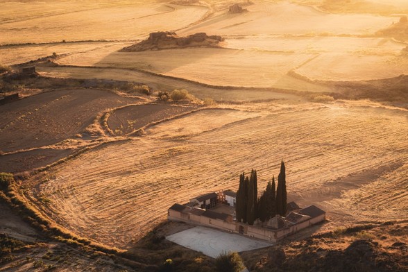 Fotografía desde un punto de vista alto donde se ve un cementerio rodeado de campos al atardecer.