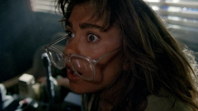A surprised woman with wide eyes wearing large, transparent glasses.