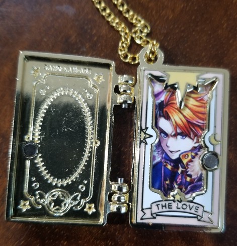 Opened locket, inside where the photo goes looks like a clown card that says "the love". A photo of grand Summoners raki is inside.