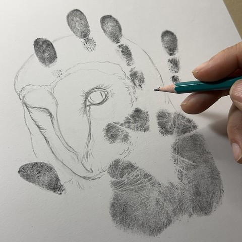 Sketch of an owl portrait inside a graphite handprint