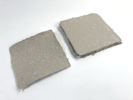 Handmade paper, with an unpressed sheet on the left, and a stack of pressed sheets on the right.