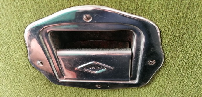Vintage silver ash tray in the back of a light green vintage bus seat.