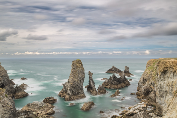 Paesaggio costiero con delle rocce piramidali in centro, lunga esposizione per appiattire il mare.