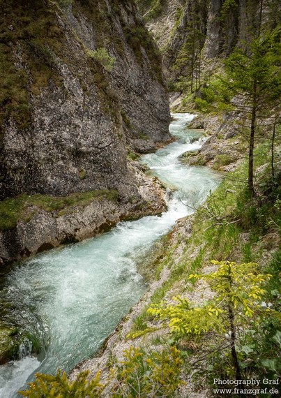 A stunning landscape scene captured in this image showcases a river running through a rocky canyon. The composition highlights the rugged beauty of nature, with the flowing water cutting through the rocky terrain. The image evokes a sense of outdoor adventure and exploration, with tags such as outdoor, nature, landscape, and mountain river emphasizing the natural elements present. The overall composition is serene and peaceful, with a focus on the natural beauty of the watercourse and surroundi…