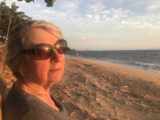 Woman on a Maui beach with the sun reflecting off of her sunglasses.