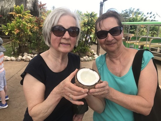 Two women holding an open coconut.