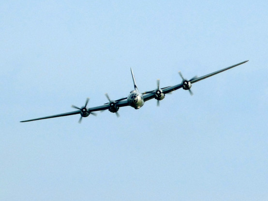 Large four-engined aircraft photographed nose on, set against a blue sky.