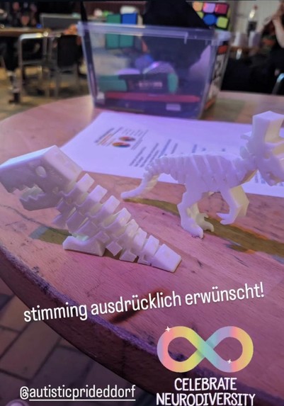 Stimming Toys in Form von Dinosauriern auf Tisch, mit Text "Stimming ausdrücklich erwünscht".
