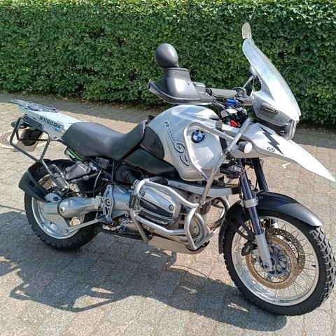 Motorrad in der Hauseinfahrt, dahinter eine Hecke.