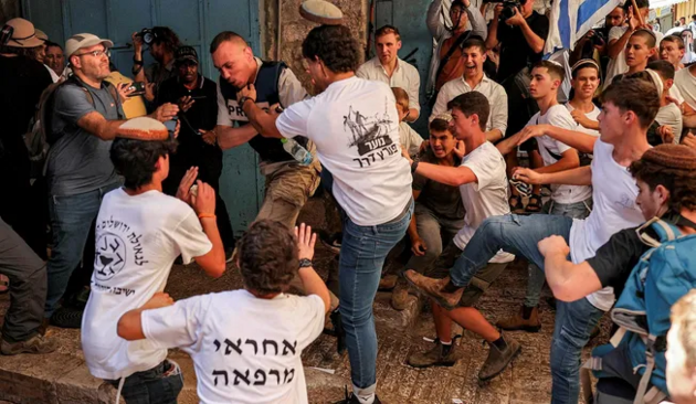 Haaretz journalist Nir Hasson and a Palestinian photojournalist get attacked by a group of Israeli youth in Jerusalem's Old City, Wednesday.Credit: AFP