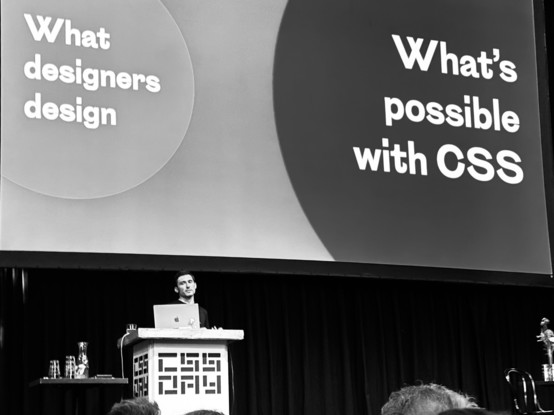 Matthias Ott on the stage of CSS Day. Slide content: a small circle with text ”What designers design“, a large circle with text “What’s possible with CSS”