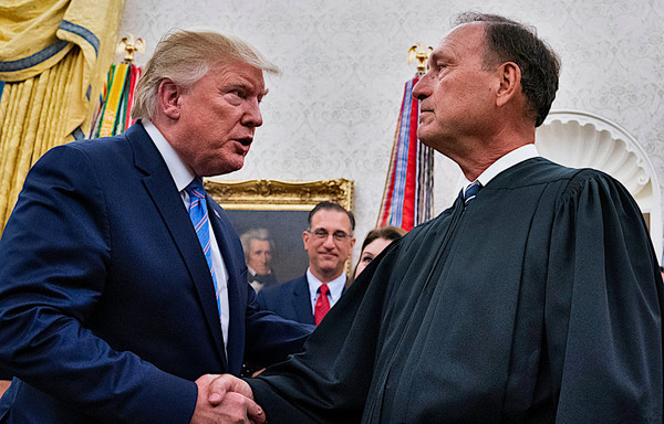 Photo of Trump during his presidency, shaking forcefully the hand of Samuel Alito in judges robes in the White House.
