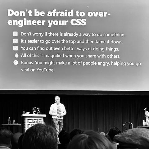 Kevin on stage. Slide content:

Don't be afraid to over-engineer your CSS

✅ Don't worry if there is already a way to do something.
✅ It's easier to go over the top and then tame it down.
✅ You can find out even better ways of doing things.
🔥 All of this is magnified when you share with others.
🙃 Bonus: You might make a lot of people angry, helping you go viral on YouTube.