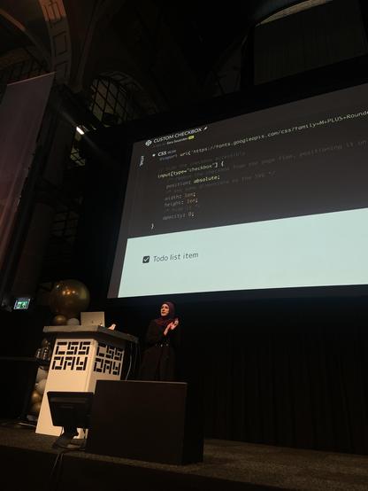 Sara on stage showing CSS that moves the actual checkbox behind the graphic