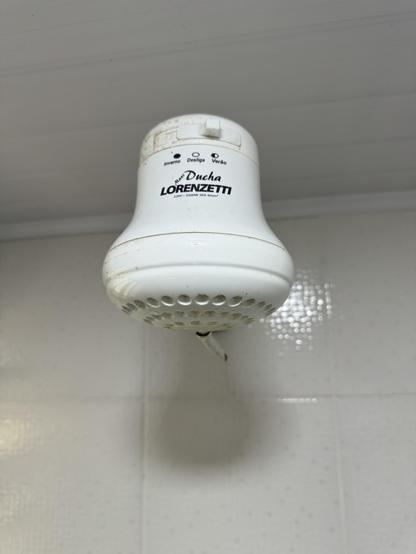 A big plastic shower head from the front saying it takes 220V. It uses electricity to heat up the water.