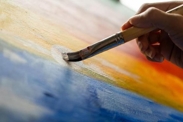 An artist painting on a canvas. Image by GBJSTOCK via Shutterstock.