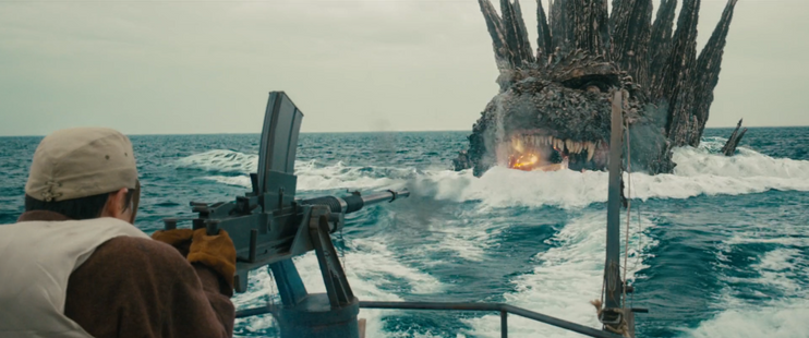 A man on a boat is aiming a large gun towards Godzilla, who is emerging from the ocean with its mouth open, emitting flames.