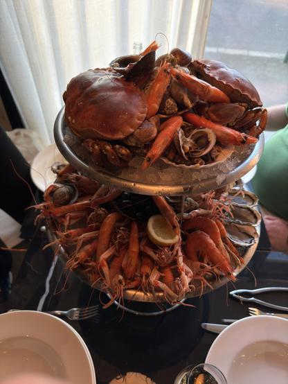 Two quite large platters of assorted seafood (crab, langoustine, oysters, red and gray prawns, winkles and more) one above the other. 