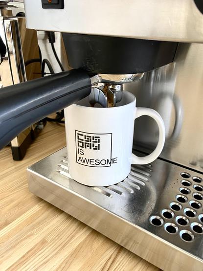 A CSS Day coffee mug being filled by a portafilter machine