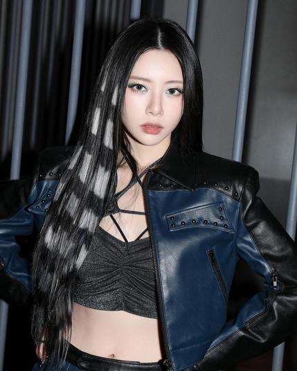 profile shot of jiu (dreamcatcher). dark hair with grey accents. she is wearing a black/dark blue outfit. leather jacket. a cool look.