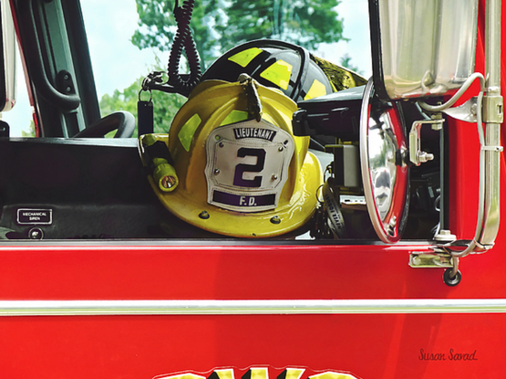 Two firemen's helmets can be seen through the fire truck's open compartment, one yellow and the other black. Within each department, the colors signify rank.