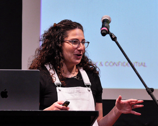 Noa Levi, speaking in front of a screen