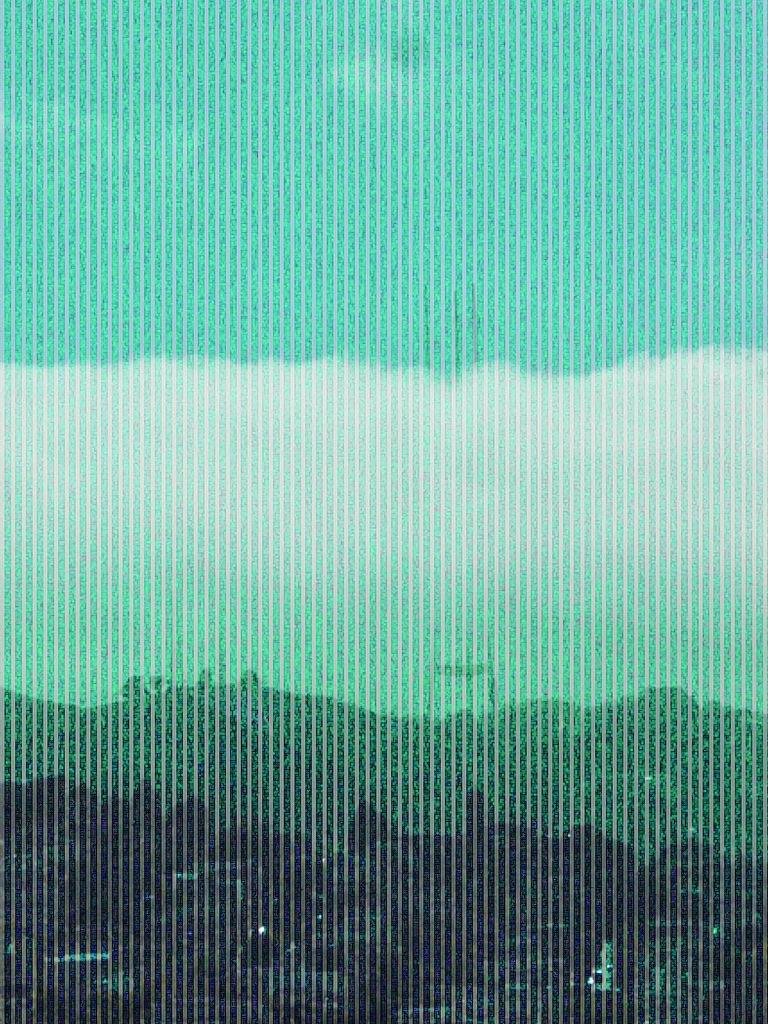 A glitched photo of Sutro Tower from far away, with the fog rolling in. There are vertical lines running on the image and a washed out blue color over the whole image. 