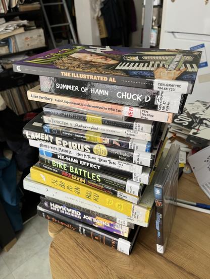Stack of 13 library books, including, The Illustrated Al; Chuck D’s, Summer of Hamn; Bill Perrine’s, Alien Territory, radical, experimental and irrelevant music in 1970s San Diego; and Christopher C King’s, Lament from Empirus, an odyssey into Europe’s oldest surviving folk music.