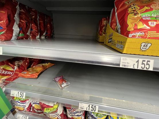 Supermarket shelves which used to hold crisps but are now empty, except for a single small packet of “crisp & juicy watermelon slices” which someone has clearly left there when picking up a crisp-multipack instead.