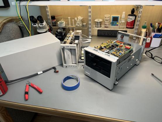 An open DLT drive cabinet on a workbench, with two half-height 5.25" floppy drives inside, stacked one on top of the other.