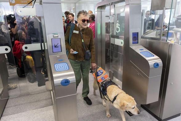 Une personne non voyante passant les portique du métro avec son chien guide