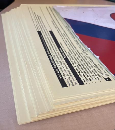 A thick stack of voter registration applications, the top one showing that it’s a new application to vote.