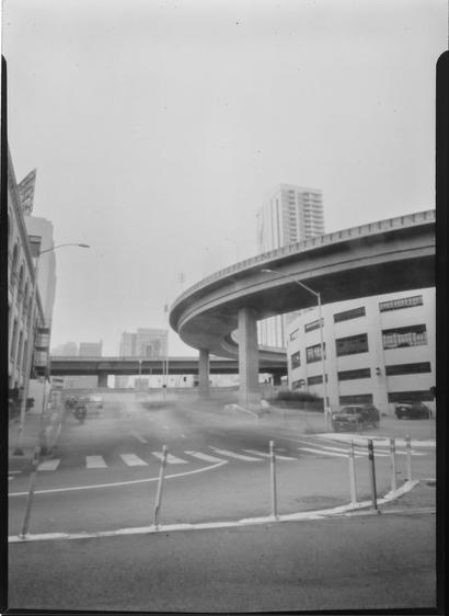 A black & white pinhole photo of a highway on-ramp