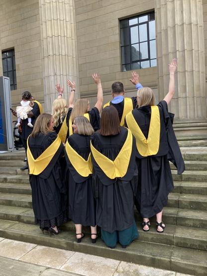 EduAT graduates celebrating in the Caird hall steps with their backs to the camera