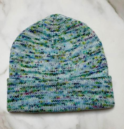 A doubled-layered hand-knit beanie in a green/blue variegated yarn 