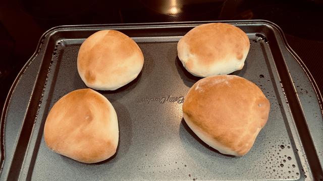 Four baked hamburger buns on a baking tray. https://www.tasteofhome.com/recipes/40-minute-hamburger-buns/