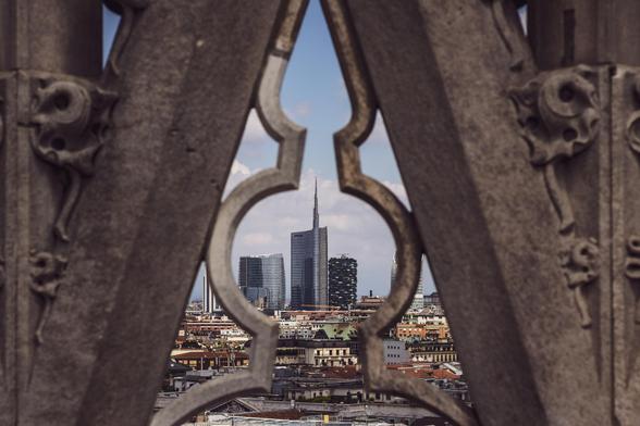 Detalles de las terrazas del Duomo de Milán enmarcando edificios actuales al fondo.