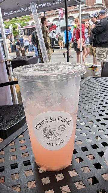 Image shows a cup of watermelon lemonade with a logo for a local business called Pours and Petals on the cup