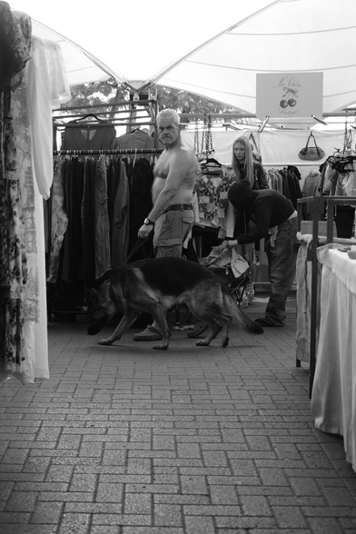 Man with a dog walks through a market
