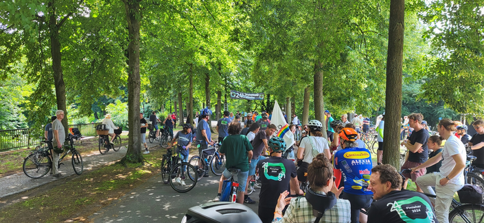 Die Promenade ist voll mit Menschen und Fahrrädern, im Hintergrund ist das 24h-Promenade-Banner über die Fahrbahn gespannt.