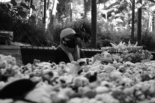 Woman at market stall sits behind a table of knitted items