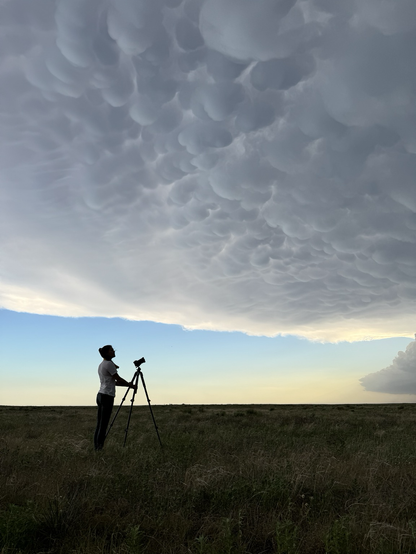 Woman with camera tripod standing under bubbly mammatus clouds