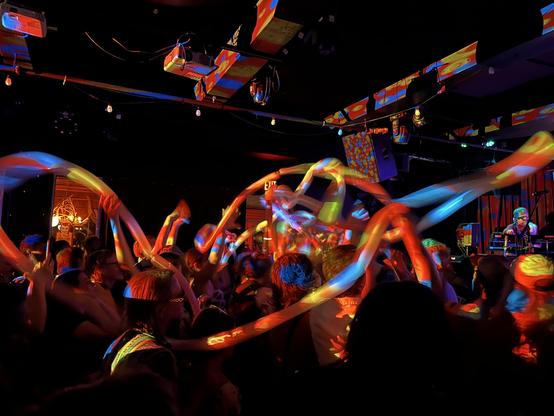 Rainbow colors are projected on a very long balloon as it is moved through the crowd at an Of Montreal concert at Sister Bar in Albuquerque, NM.
