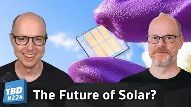 Matt and Sean Ferrell in front of a gloved hand holding a Quantum Dot Solar Cell