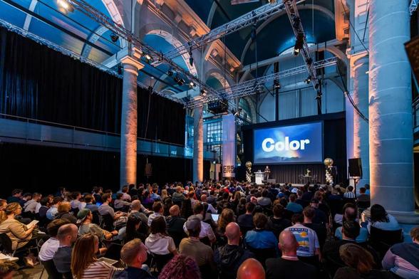 A view that shows the audience and the venue of CSS Day and a slide with a rainbow and one huge word: Color.