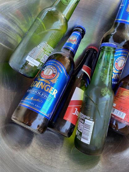 Verschillende soorten drankjes in glazen flessen in een metalen kom