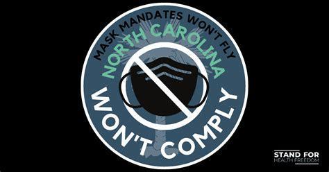 Black background, grey circle, mask in middle, the a mark out sign. Words say Mask Mandate won't fly, North Carolina, won't comply