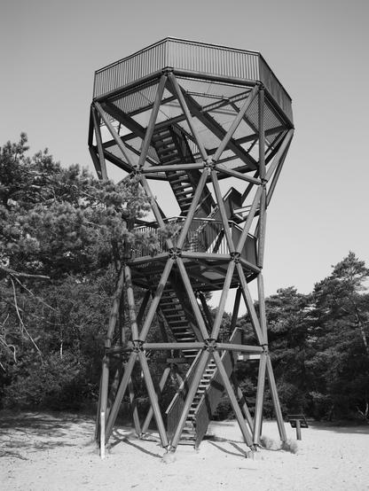 A lookout tower, on top of sand, with trees surrounding it