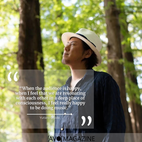 Yutaro Ogida stands in front of a couple of trees and looks away from the camera. He is wearing a dark blue shirt and a fedora. On top of the photo a quote is placed from the interview he had with AVO Magazine: "When the audience is happy, when I feel that we are resonating with each other in a deep place of consciousness, I feel really happy to be doing music."