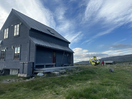 Mountain hut with a yellow helicopter (ambulance) next to it.